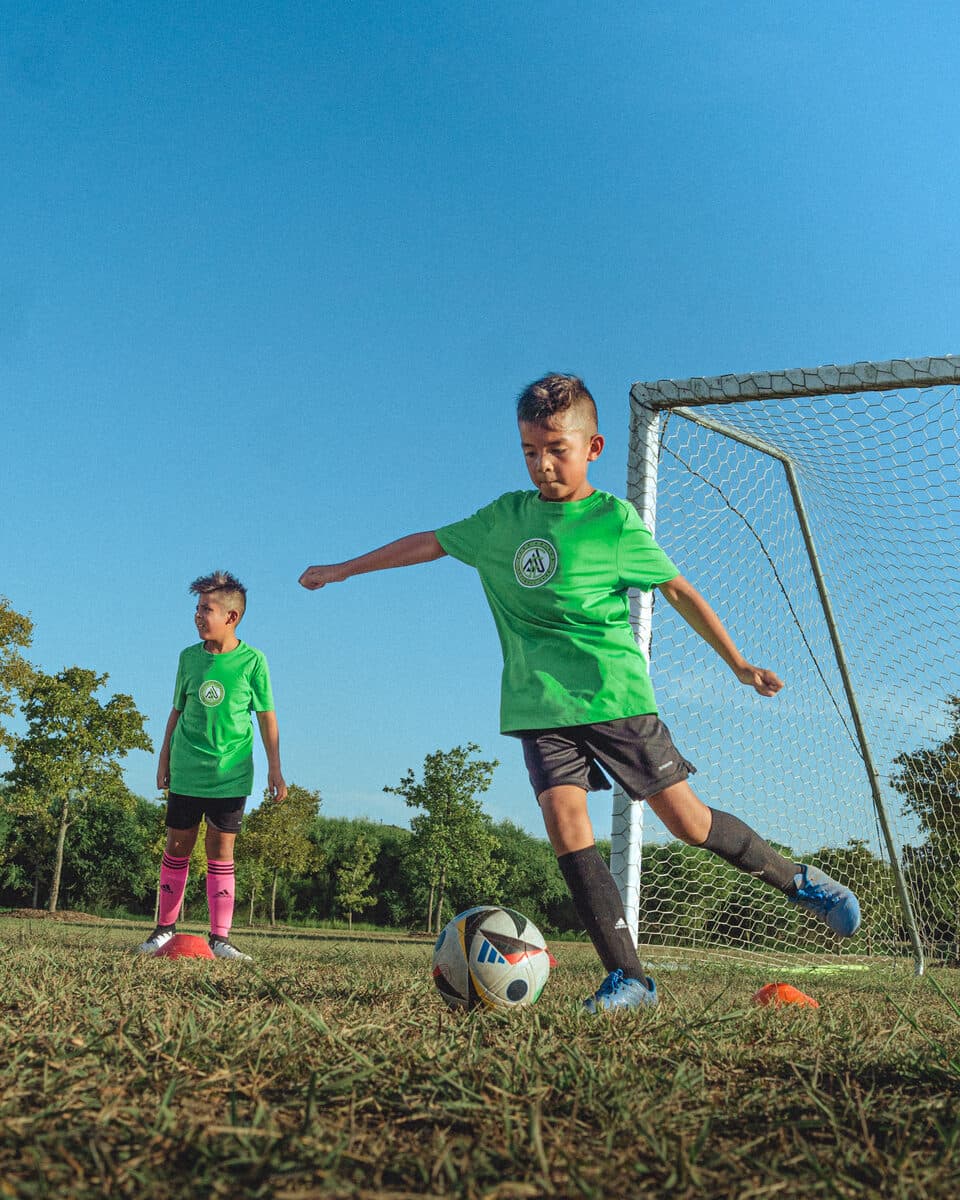 Apex United FC player striking the ball on a sunny match day in San Antonio