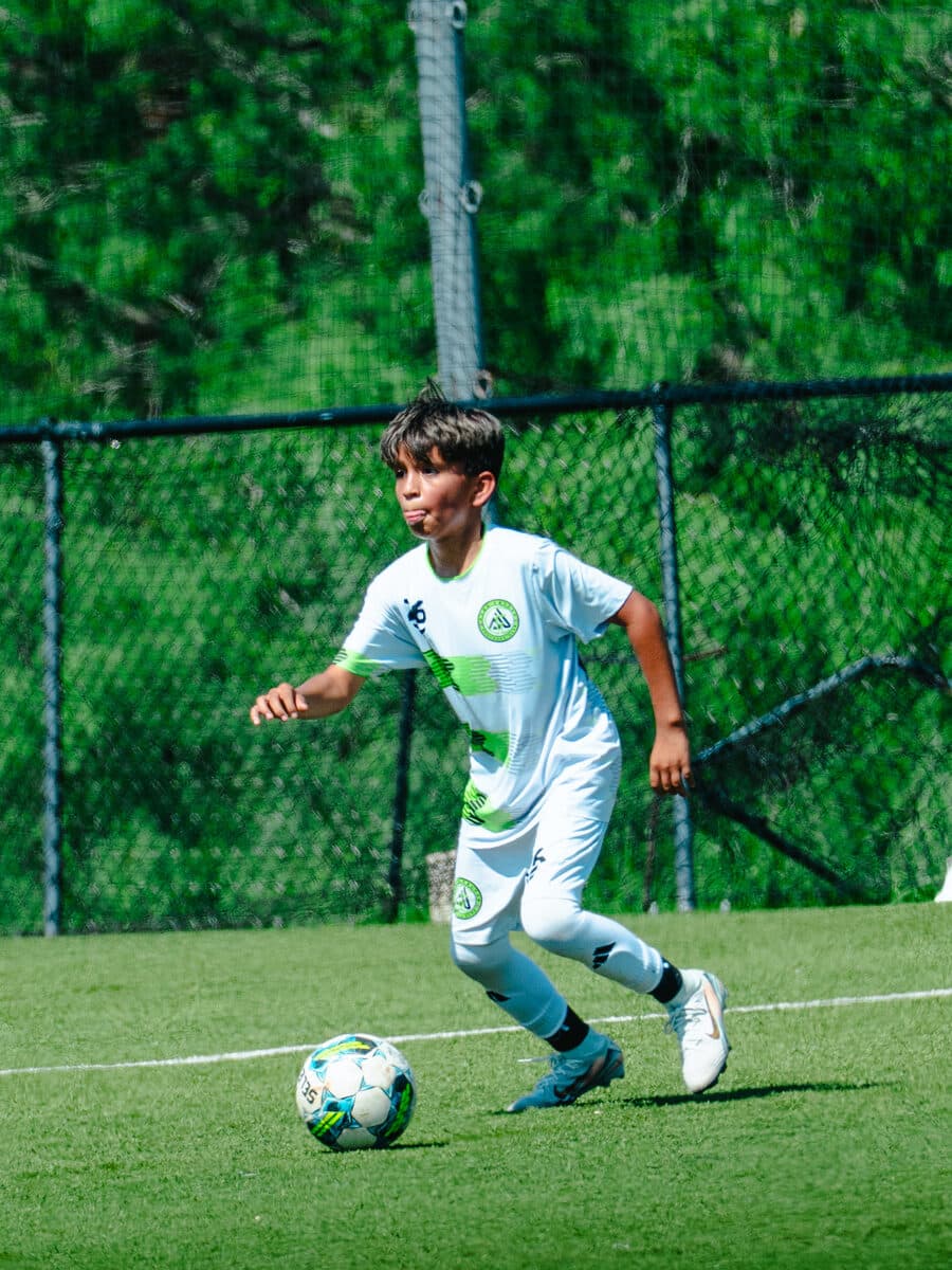 Apex United FC player dribbling in the green and white home kit in San Antonio